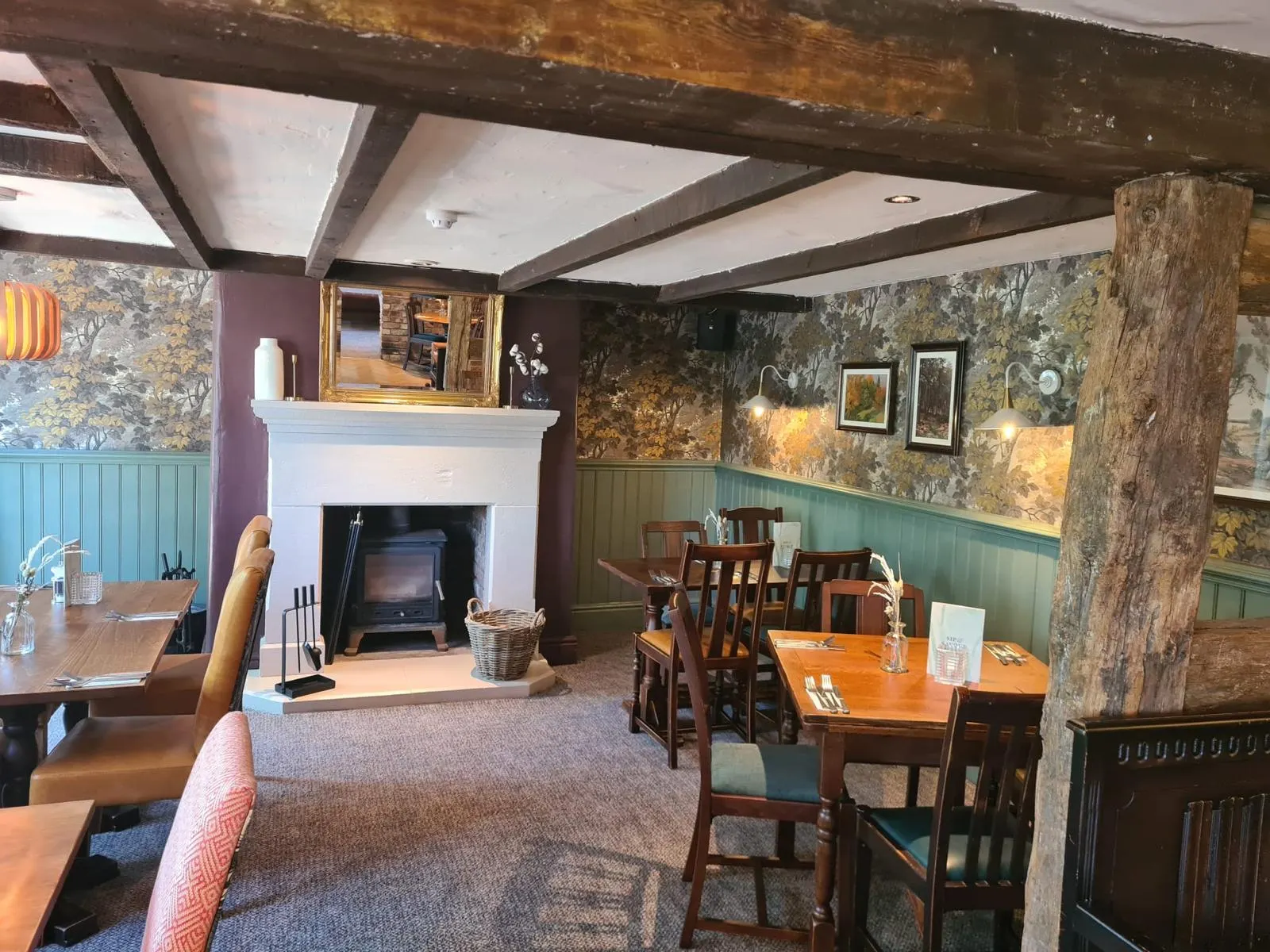 Pub dining room with fireplace, sage panelling and patterned wallpaper