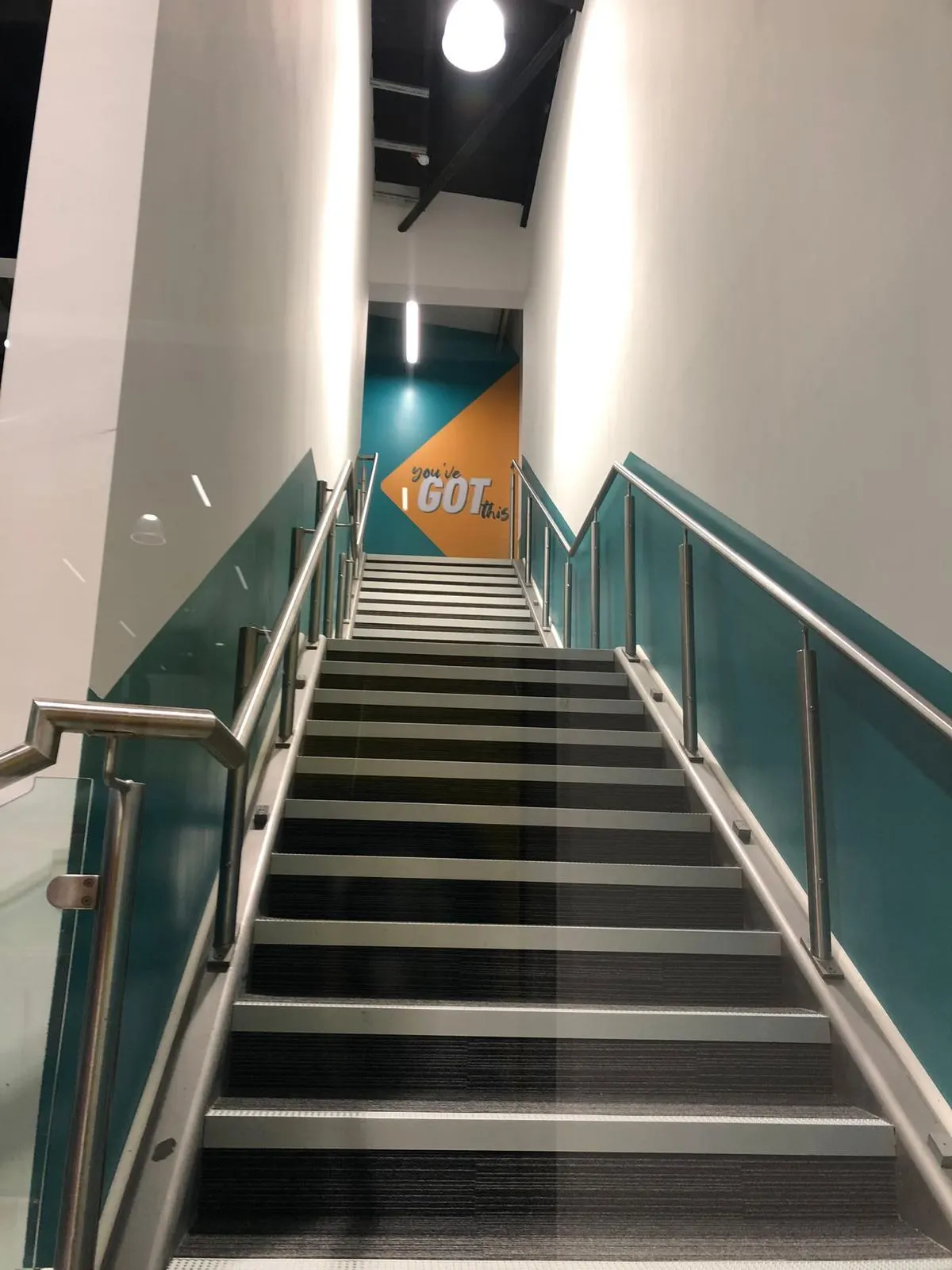 Staircase with teal and white painted walls in a gym