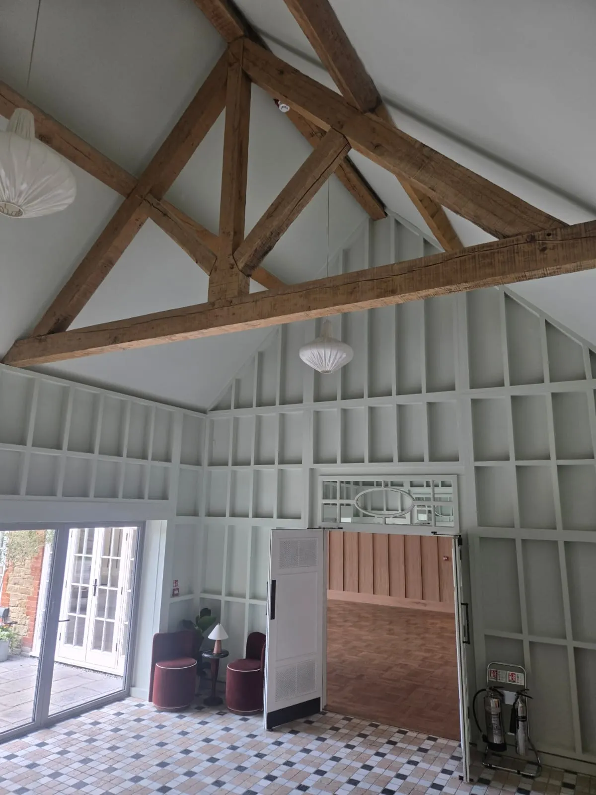 Room with grey painted wall panelling beneath an exposed oak truss