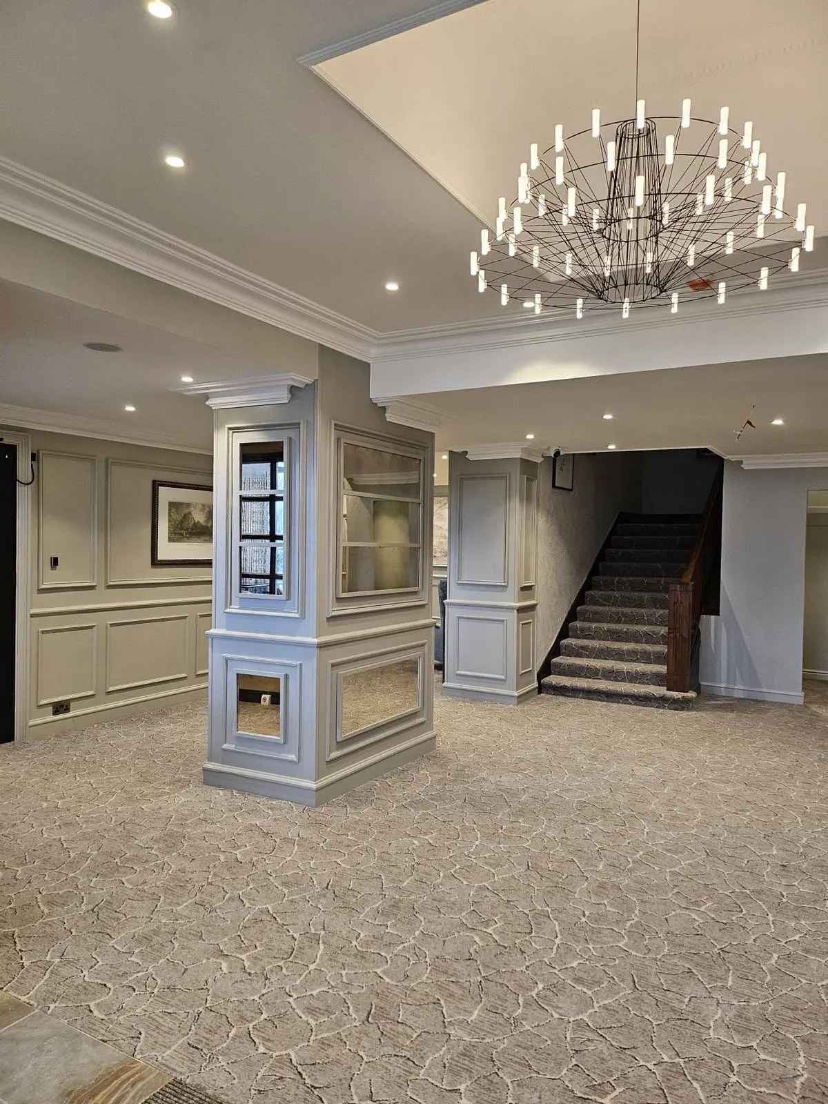 Reception with painted panelled column, staircase and chandelier