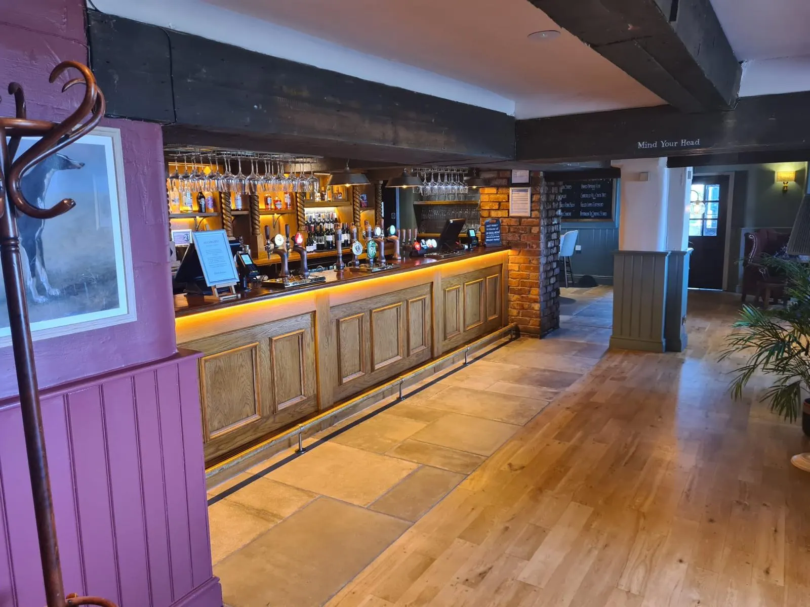Pub bar with purple painted panelling and a backlit timber counter