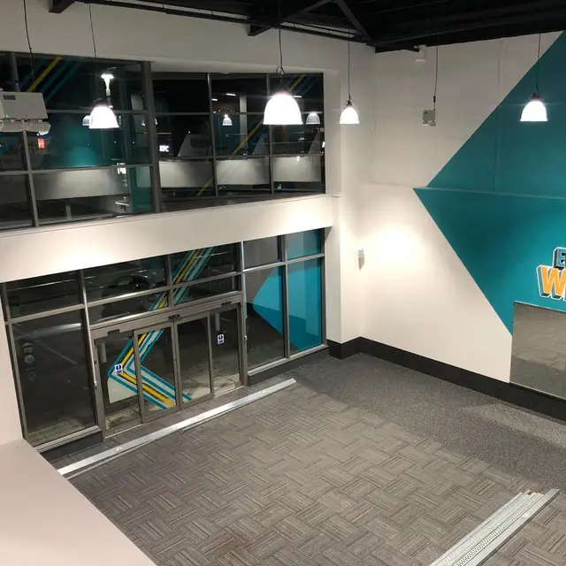 Gym entrance with teal feature wall and mezzanine glazing