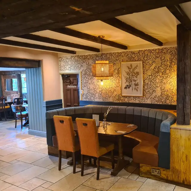 Pub booth seating with patterned wallpaper and blue panelling