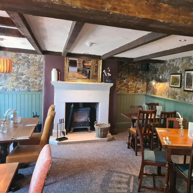 Pub dining room with fireplace, sage panelling and patterned wallpaper
