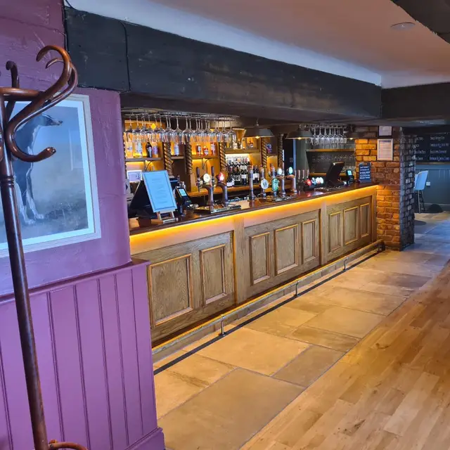 Pub bar with purple painted panelling and a backlit timber counter