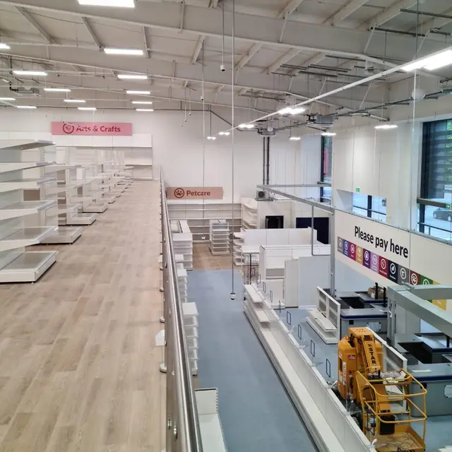 Retail store mezzanine view over white shelving and walkways