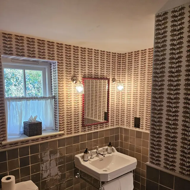 Cloakroom with patterned wallpaper and tiled walls