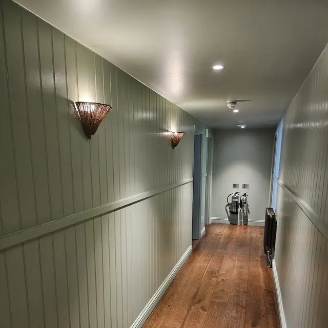 Corridor with sage green tongue-and-groove panelling and oak floor