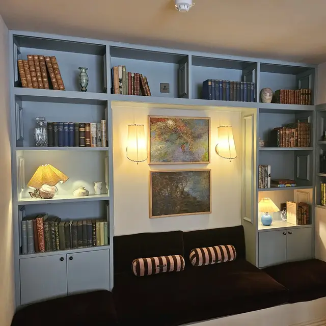Built-in bookshelves painted pale blue around a window seat