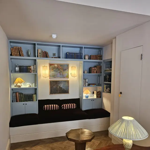Reading nook with pale blue painted bookcases and parquet floor