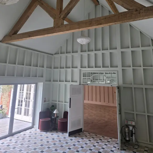 Room with grey painted wall panelling beneath an exposed oak truss