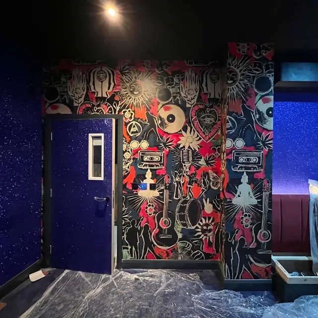 Music-themed feature wallpaper and painted blue door in a venue