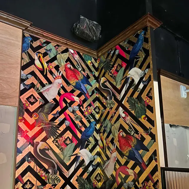 Bold bird-print wallpaper above dark timber panelling